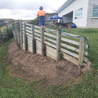 Worker inspecting leaning timber retaining wall prior to reconstruction in Napier