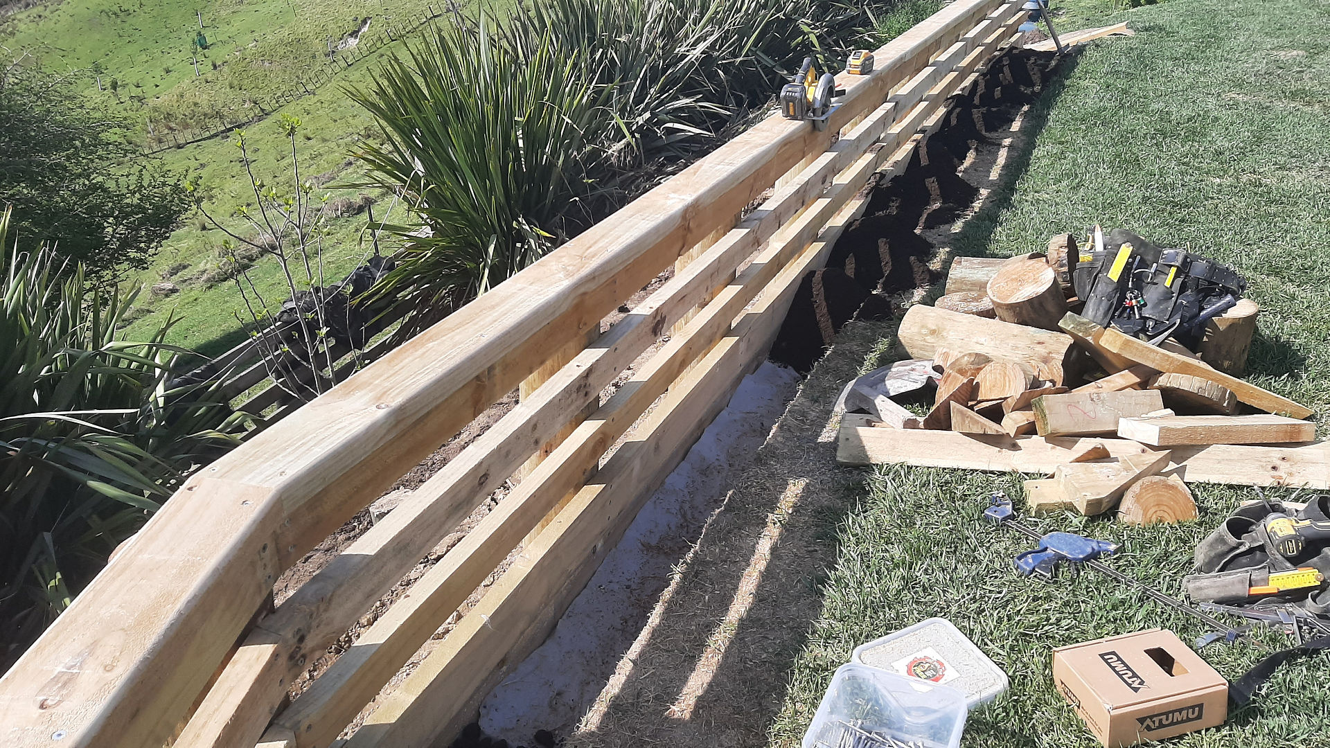 Close-up of newly fixed timber handrail boards on retaining wall with tools on site in Napier