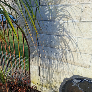 Vertical crack in a concrete block boundary wall showing structural movement before replacement with