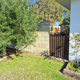 Boundary wall partially demolished before replacement with a timber and Smart Coloursteel fence in N