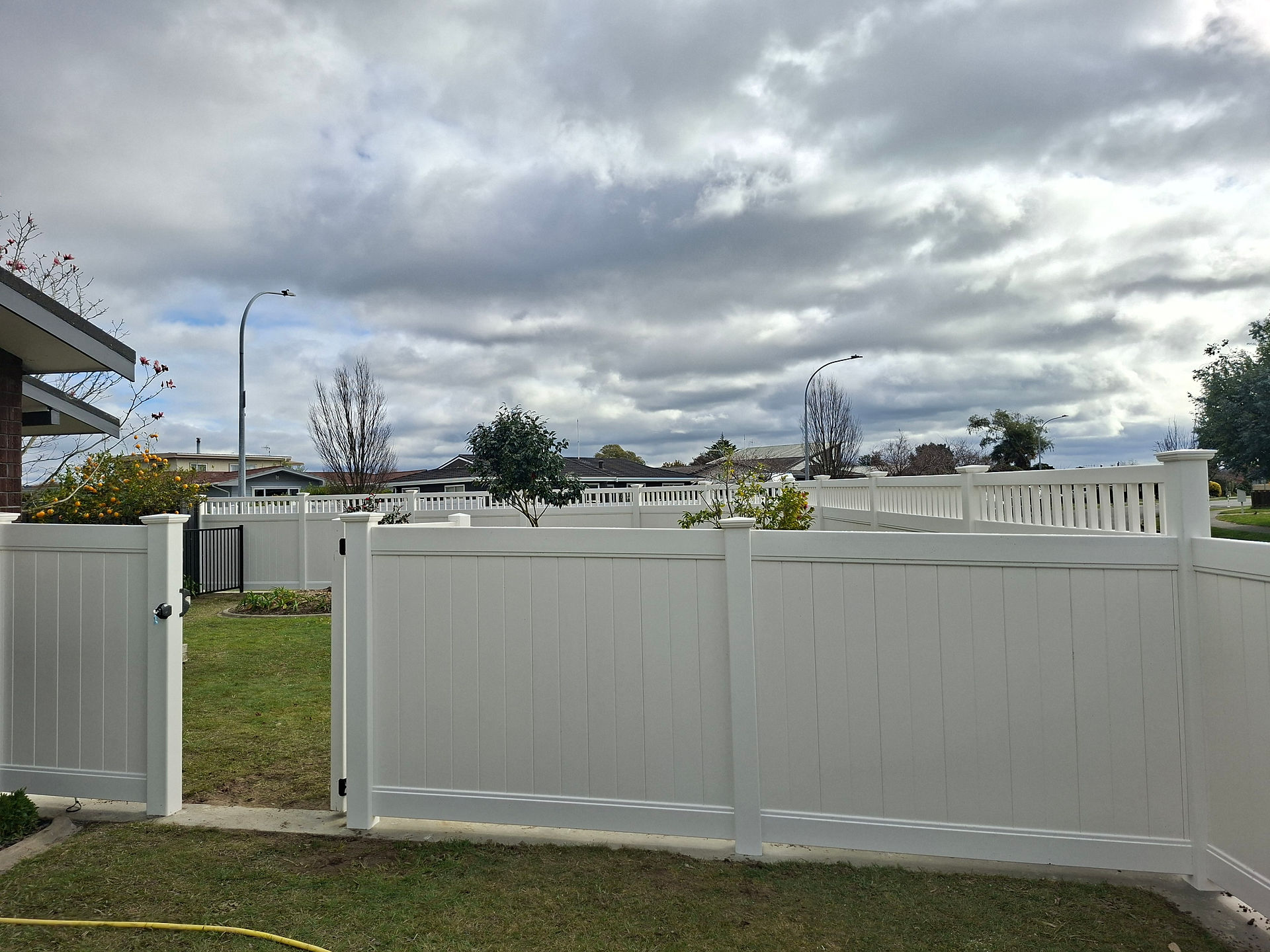 Workers installing durable low-maintenance PVC fencing for a residential property.