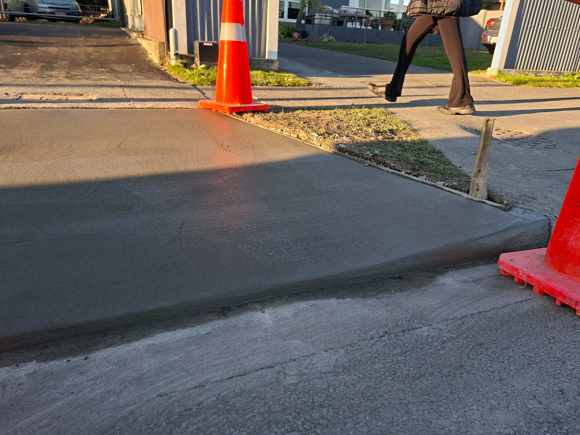 Freshly placed concrete driveway in Hawke's Bay being screeded to create a smooth, level surface bef