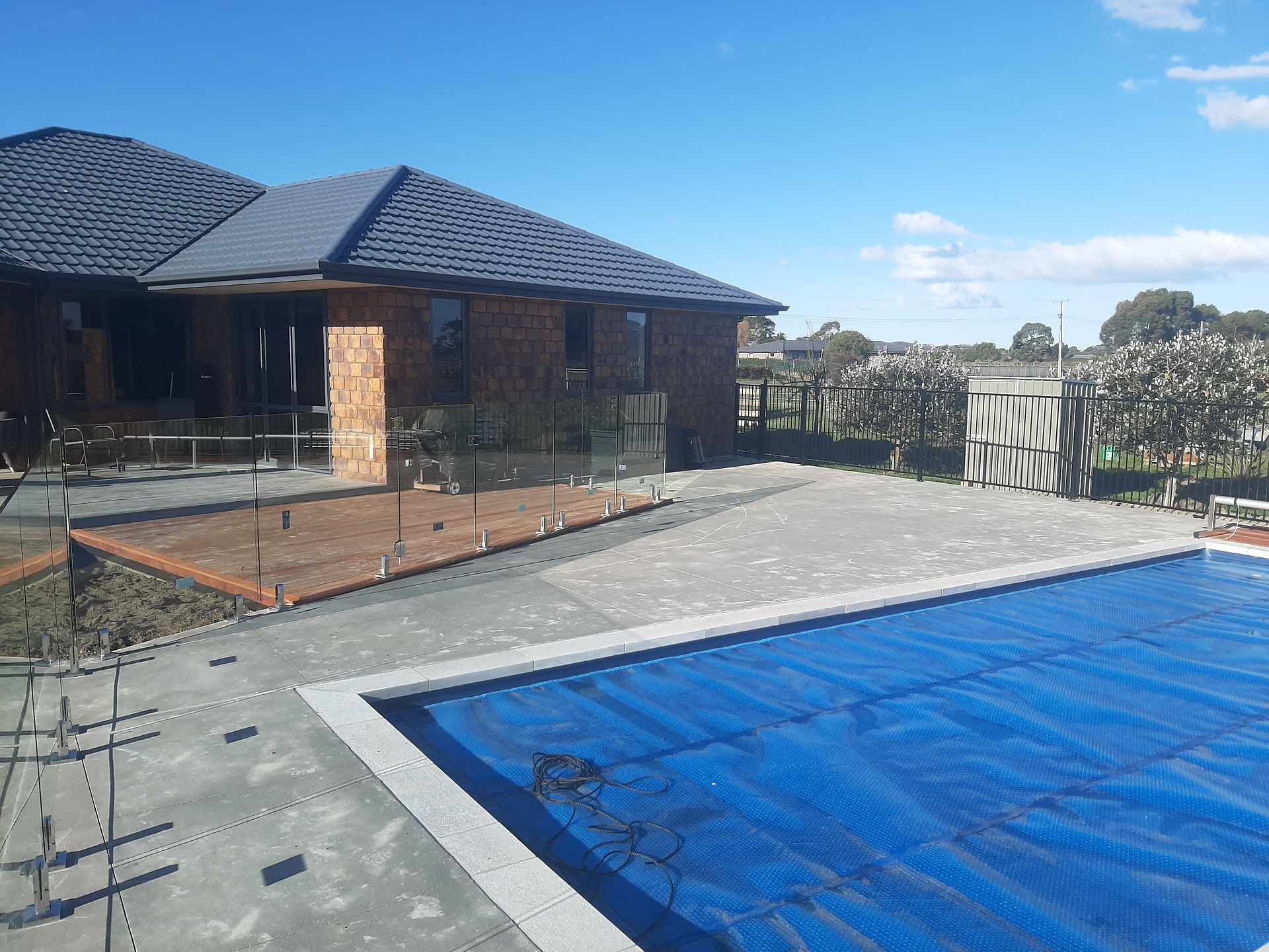 Completed swimming pool with concrete surround, glass fencing and Kwila decking in Napier