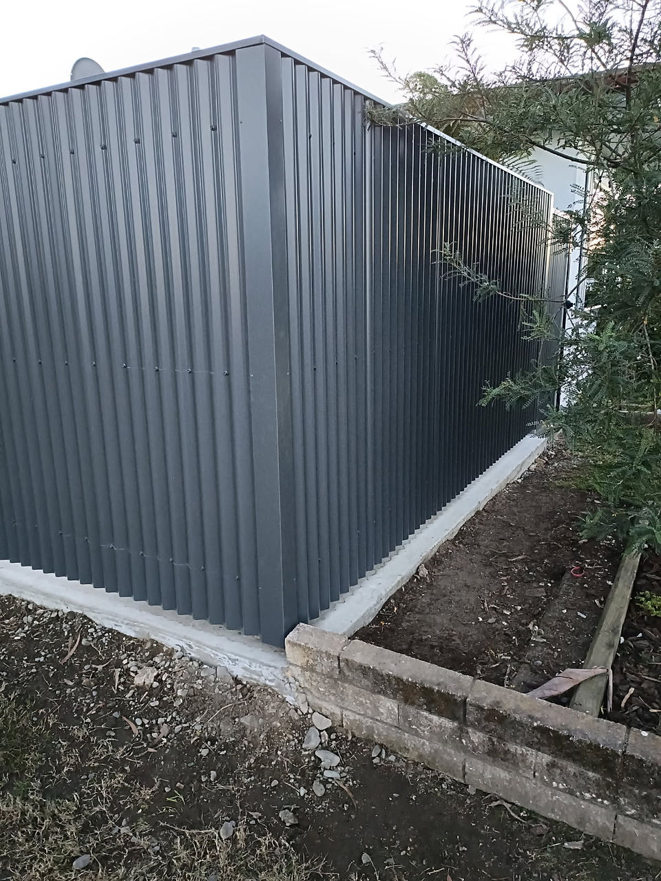 Completed Smart Coloursteel boundary fence installed on a reinforced concrete nib replacing a cracke