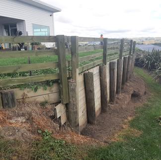 Close view of bowed wood retaining wall posts under soil pressure before repair in Napier