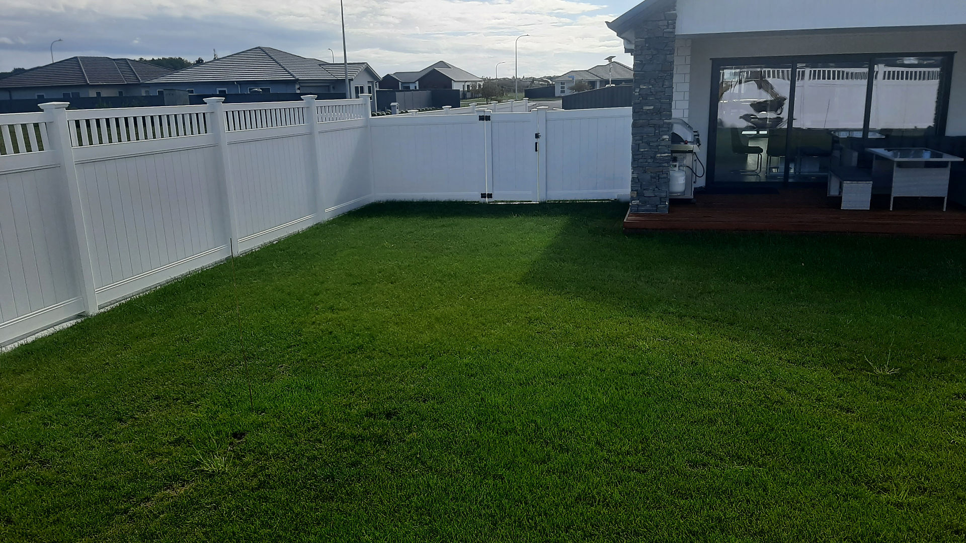 Completed PVC fence and double gate enclosing backyard area in Hastings