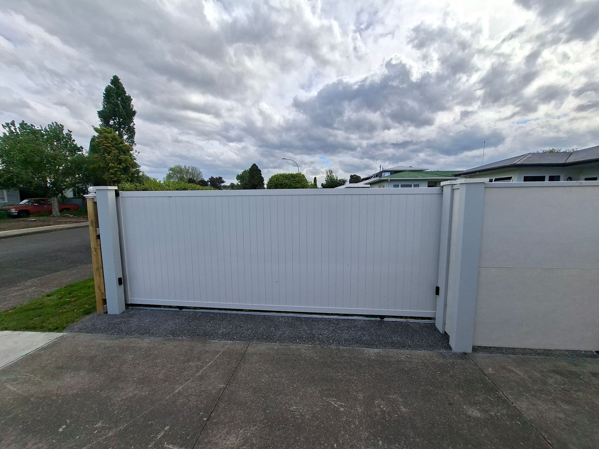 Closed sliding driveway gate in white PVC fencing at front boundary in Hastings