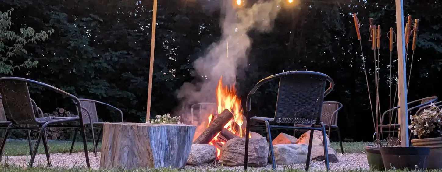 Fieldstone fire pit and pea-stone gathering area lit by string lights in Niles, MI
