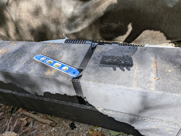 Unilock Siena Edge Midnight Charcoal retaining wall installation with wall face drain and drain tile