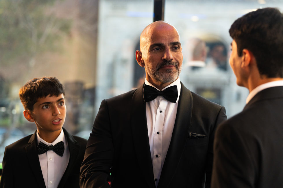 a man in a tuxedo with a bow tie stands next to two other men