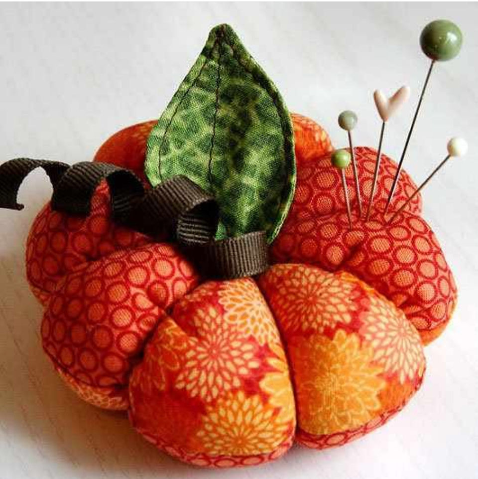 A fabric pin cushion shaped like a pumpkin