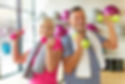 Older woman and man hold dumb bells in a gym