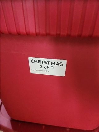 Red plastic bin with white label stating Christmas 2 of 7