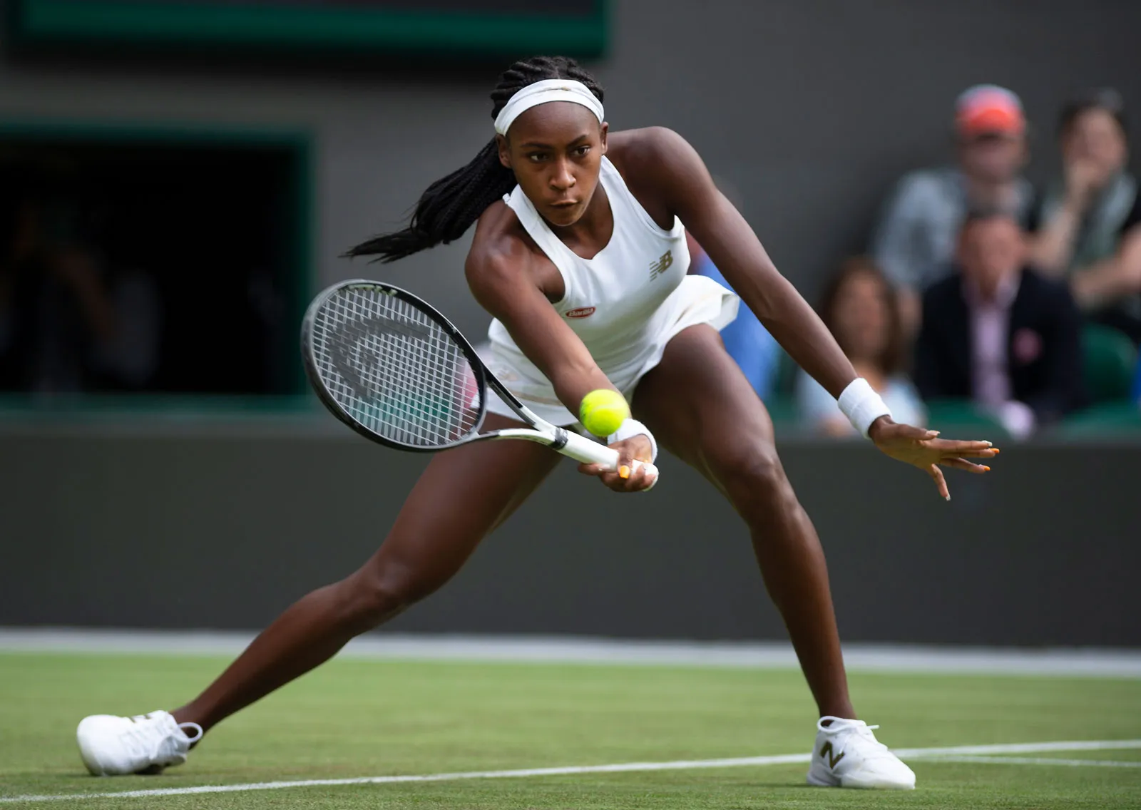 Tennis player Coco Gauff chips a forehand shot while playing on the grass court at Wimbledon