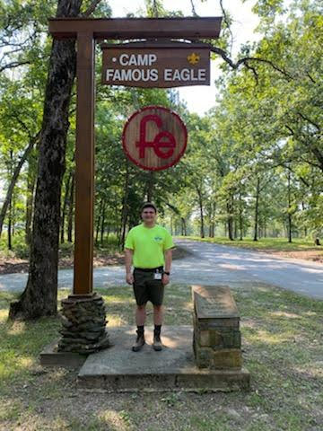 Boy Scout counselor standing under a summer camp sign