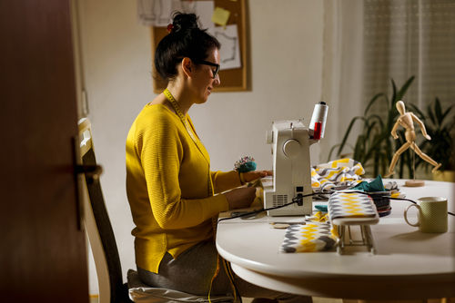 Woman sitting at a table and sewing on a sewing machine