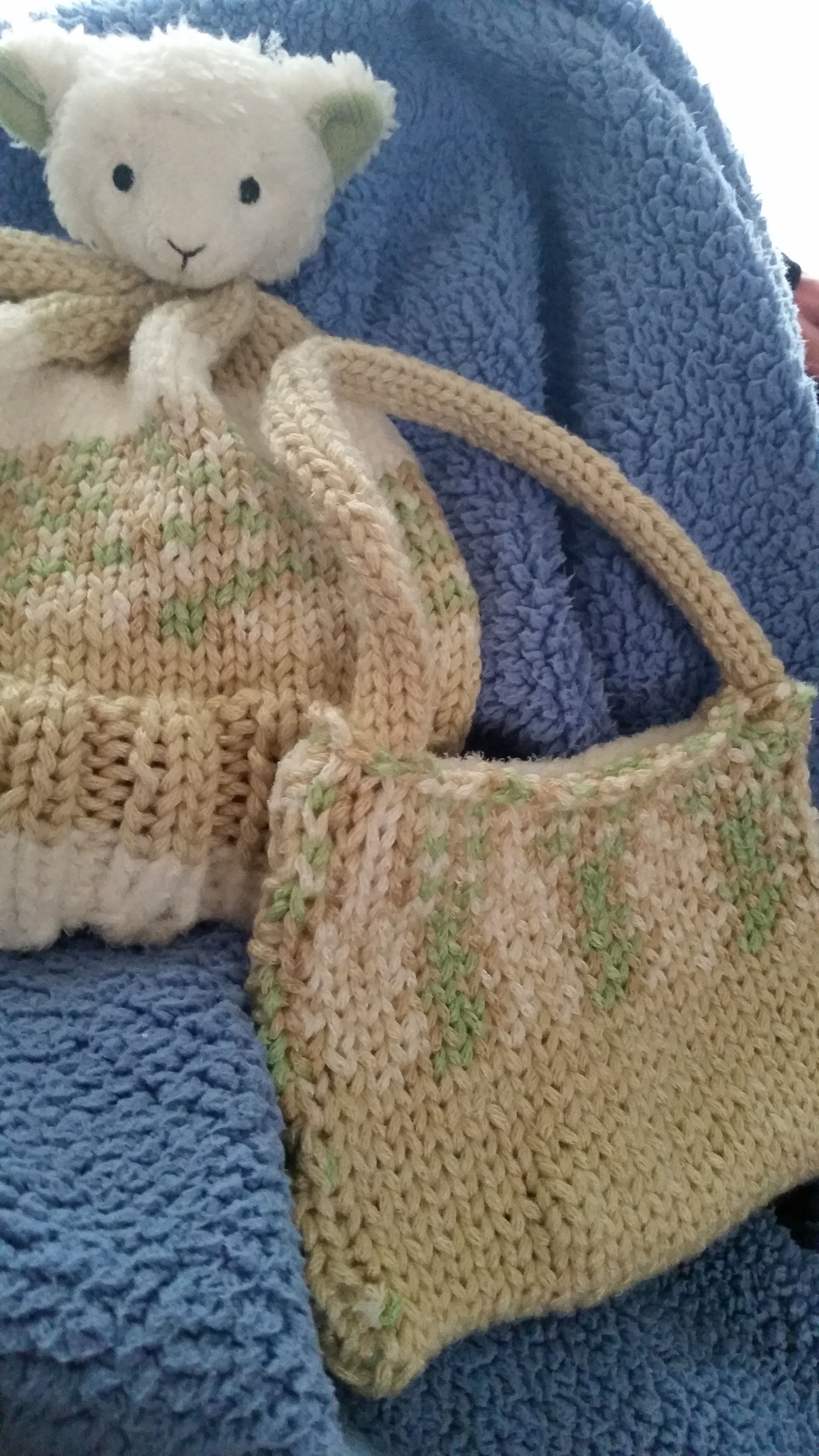 Knitted hat with a lamb head as a pom pom on top alongside a matching knitted purse
