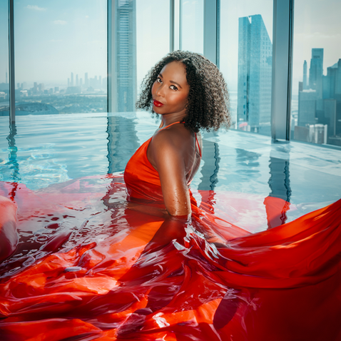 Creative flying dress photoshoot. Lady wearing a red flying dress in a swimming pool