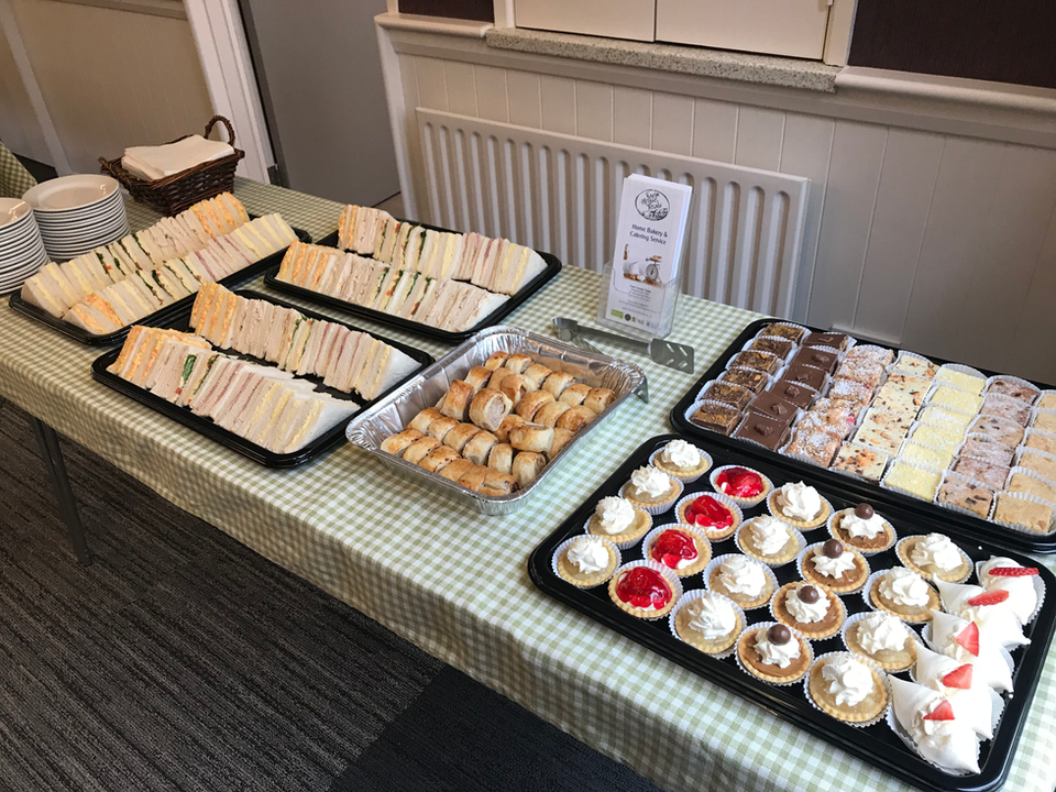 Funeral catering setup with full buffet service – traybakes, sandwiches and tea cups.
