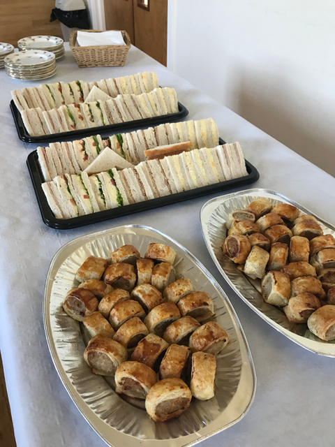 Funeral food table with fine china, sausage rolls, sandwiches and cream pastries – ready for delivery in Lisburn.