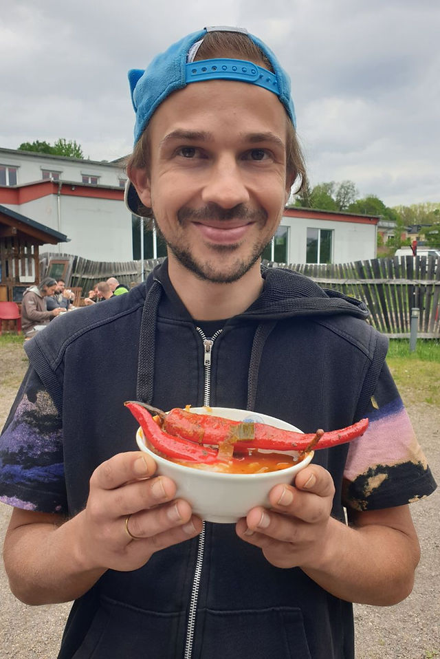 Steven Eich hält beim Männerfestival Chemnitz 2026 eine Schale Eintopf mit roter Chili in den Händen.