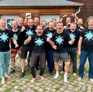 Organisations- und Helferteam des Männerfestivals Chemnitz 2026 vor der Holzkirche Chemnitz auf dem Festivalgelände.