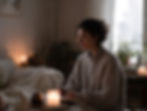 Woman reflecting in a cozy winter home with candlelight and soft textures.