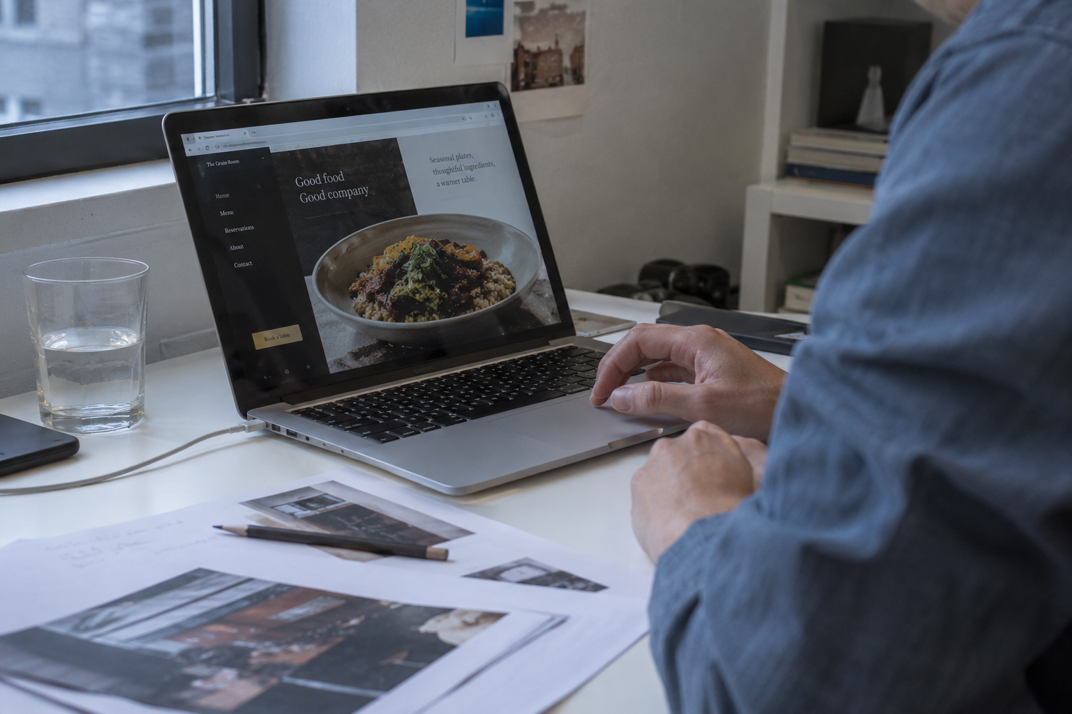 Designer working on a restaurant website beside a studio window