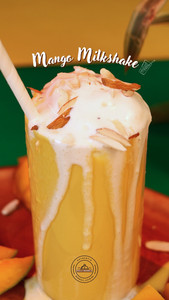 Thick mango milkshake topped with cream and almonds, served with fresh sliced mango at Palli Bangla Restaurant