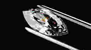 Large marquise shaped diamond being held by tweezers against black background