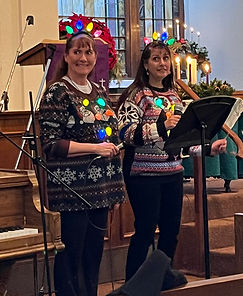 Two parishioners decorated in Christmas lights and festive sweaters
