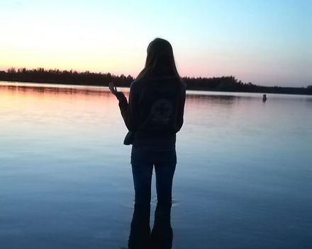 a picture of me, standing in a lake facing the sunset
