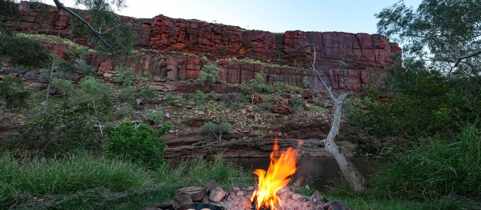 Camp oven cooking on an open fire at George Gorge with sheer red rock cliffs in the background, West Pilbara Western Australia