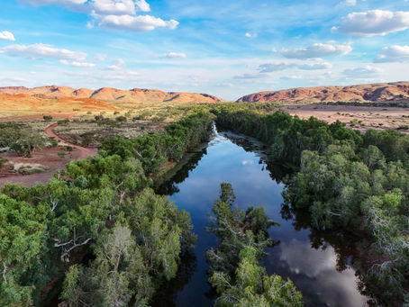 Aerial view of glassy water reflections at Coongan Pool with red Pilbara ranges in the background, near Marble Bar WA.