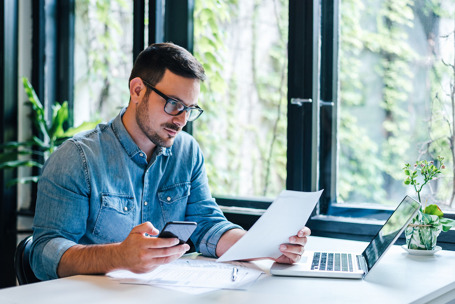 Man looking at paper and phone