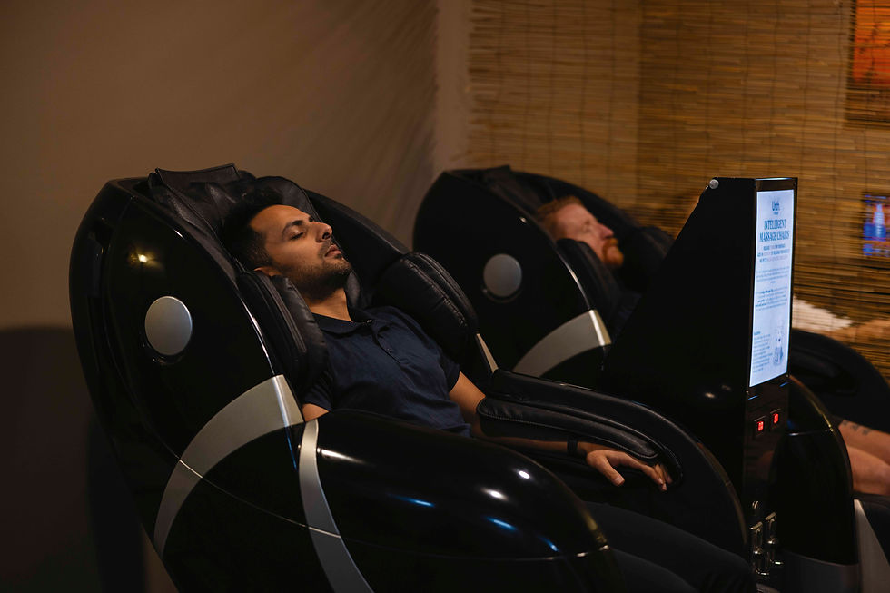 Two men relax in black massage chairs, eyes closed. Screen displays "INTELLIGENT MASSAGE CHAIRS." Warm, dimly lit room with bamboo décor.