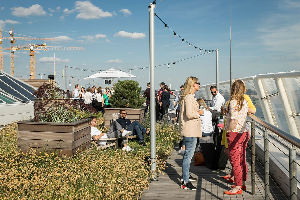 Teilnehmende stehen auf der Dachterrasse und genießen einen Sundowner
