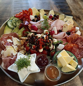 Bunt angerichtete Platte mit Käse, Wurst, Gemüse und Dips.