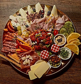 Große Platte mit Wurst, Käse, Obst und verschiedenen Dips.