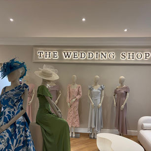 Mother of the Bride boutique interior with central dress display, timber flooring, soft lighting, and neutral palette