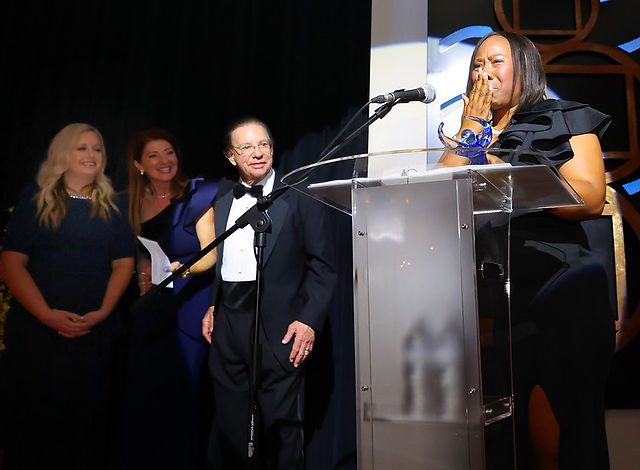 Woman at podium, others watch; Inspire Gala honors area philanthropists and nonprofits.
