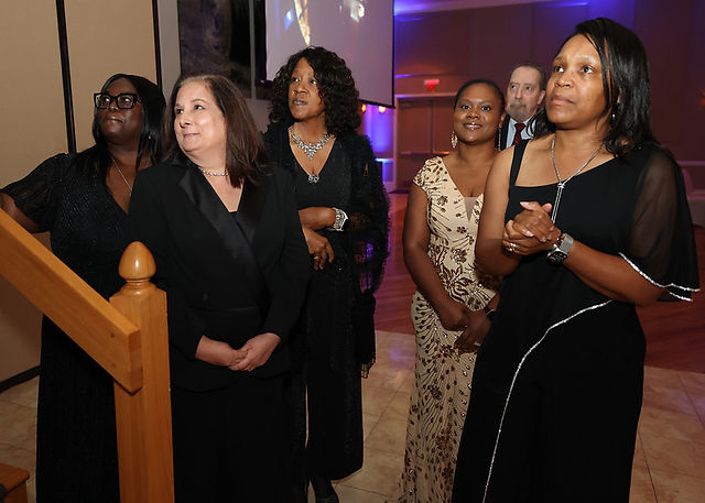 Group of women attending a formal gala event looking upwards. Inspire Gala honors.