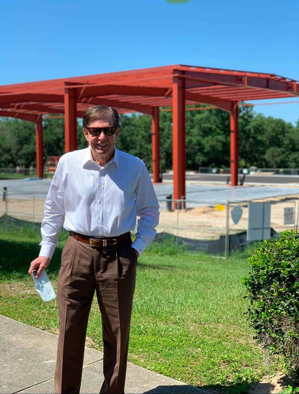 Frank DeLuca  stands near a red structure Frank DeLuca YMCA Sportsplex in sunny outdoor setting.
