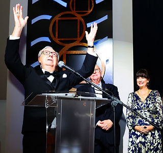 Man speaking at podium with arms raised; Inspire Gala honors area philanthropists.