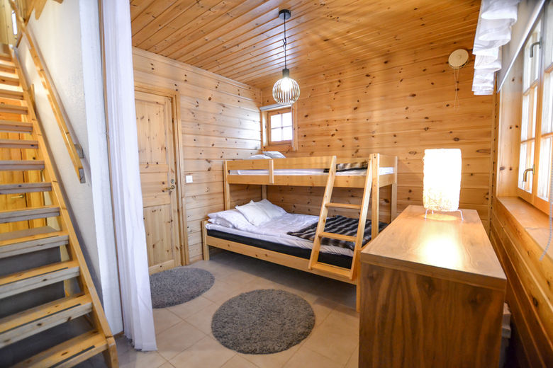 Bedroom with bunk bed and wooden decor in Lukkohalla log cabin, Ukkohalla Finland.