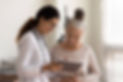happy female doctor senior patient look tablet screen discuss treatment