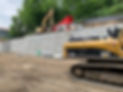 Morden Construction excavator, digger, and dump truck working along a large retaining wall of bricks during lakeshore landscaping and site preparation at a Six Mile Lake property
