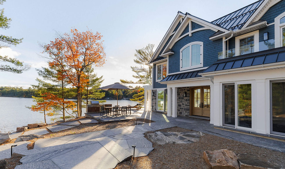 Waterfront cottage with flagstone pathways, lakeside patio, outdoor dining area, BBQ space, and fall landscape design creating an inviting outdoor living space on a Georgian Bay property.