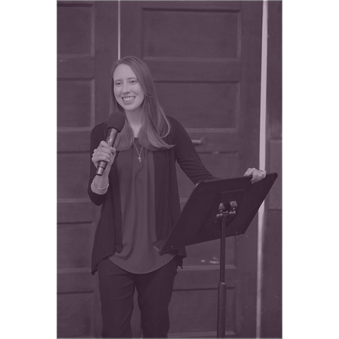 Brooke Stevens behind a podium, holding a mic