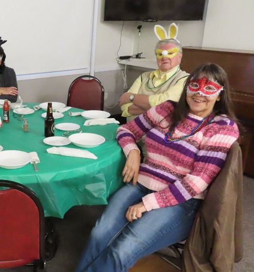 guests sitting at a table wearing different coloured Mardis Gras masks